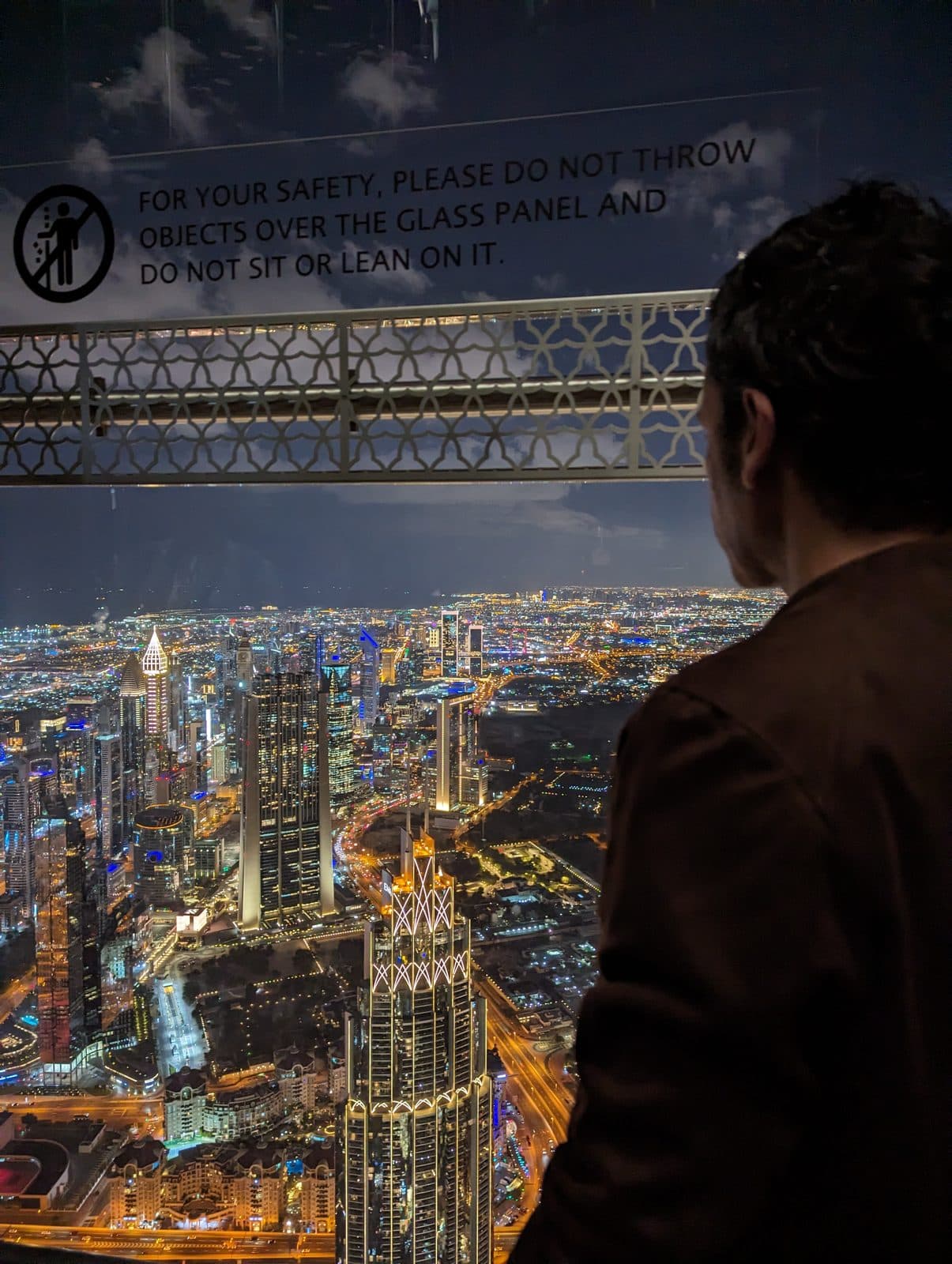 Diego looking out over Dubai's lit skyline from the Burj Khalifa Silver-tier observation deck