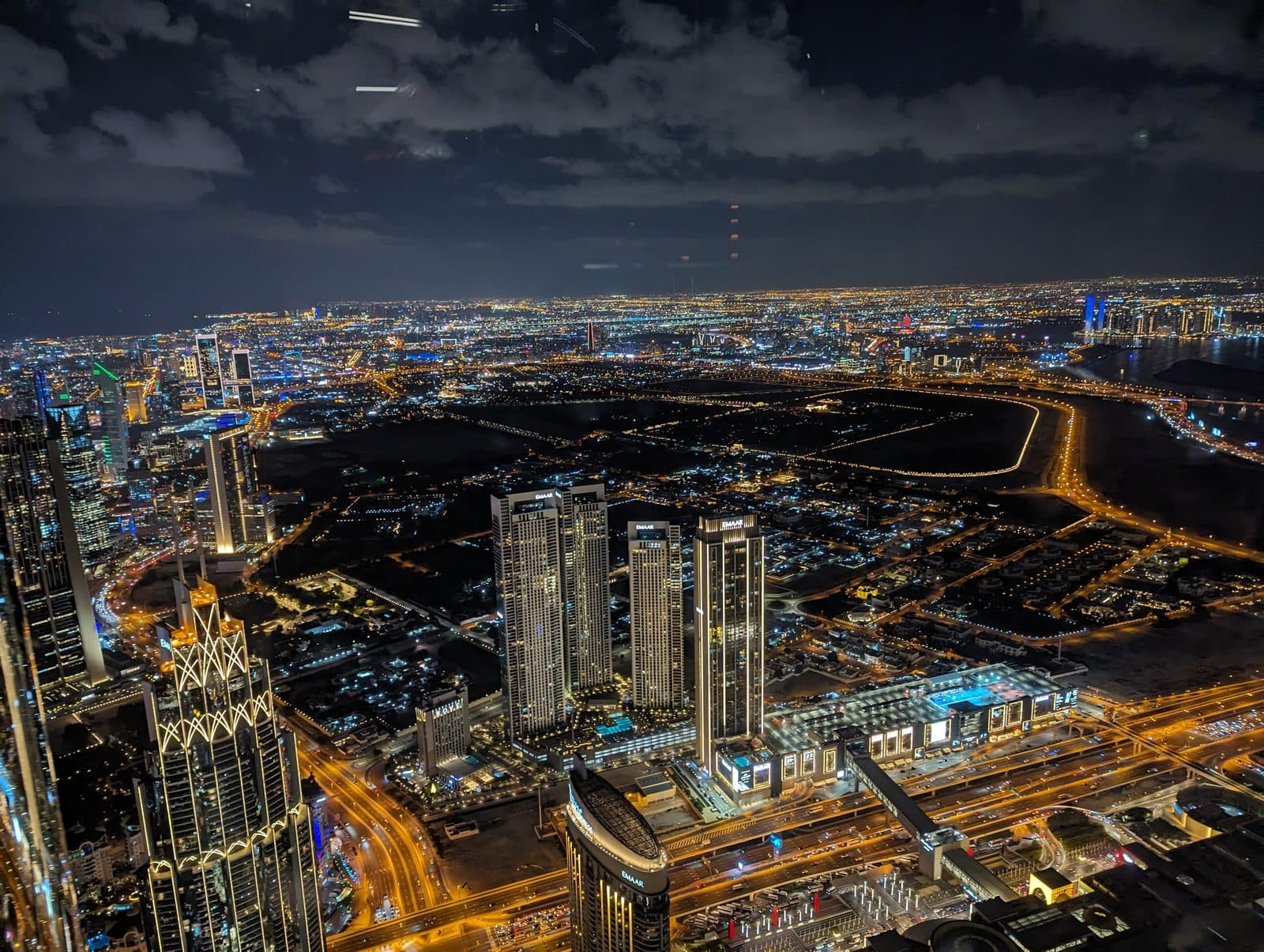 Night view over Dubai from the Burj Khalifa observation deck, looking out over the lit Downtown skyline