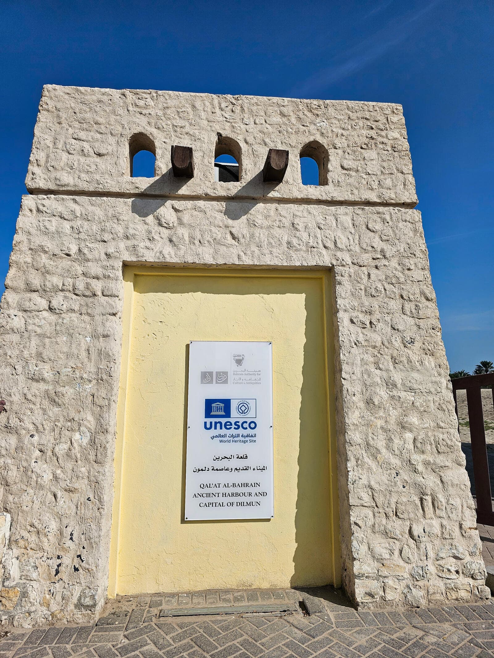 The official UNESCO World Heritage plaque at the entrance to Qal'at al-Bahrain, naming it Ancient Harbour and Capital of Dilmun
